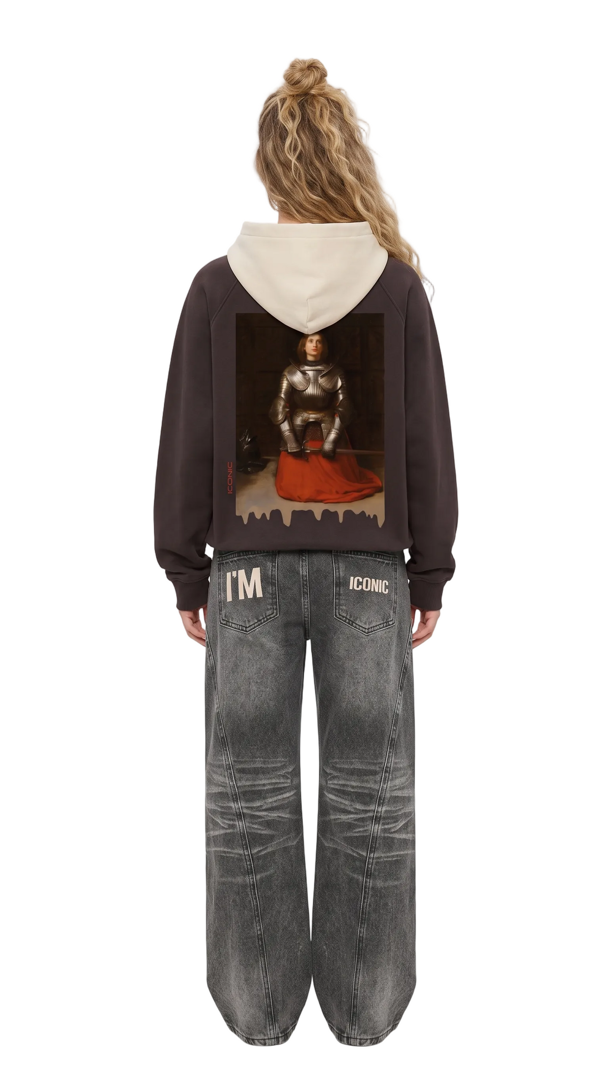 A model shown from the back wearing a dark brown hoodie with a cream hood and a large graphic print on the back, paired with distressed gray jeans.